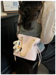Detail of pink quilted bucket bag with gold chain and horse charm over the shoulder