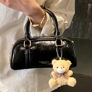 Chic black patent leather pillow bag with top handle and cute teddy bear charm