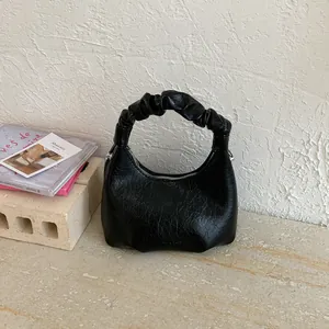Detailed view of black wrinkled leather crescent bag with stylish ruched handle design