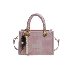 Sac cabas rose texturé avec poignées tressées et breloque en perles sur fond blanc