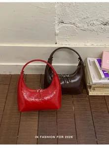 Detail von roten und braunen Hobo-Taschen mit glänzendem Faltenleder und Halbmondform