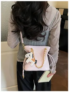 Close-up of pink quilted bucket bag with gold chain strap and horse charm on model