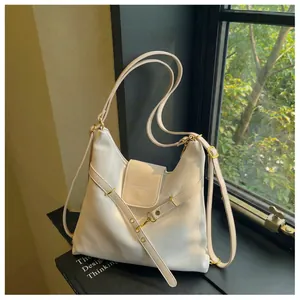 Detail van witte gewaxte lederen draagtas met gouden hardware en merklogo-opdruk op tas