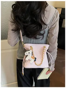 Rear view of model wearing a light pink quilted bucket bag with golden chain strap