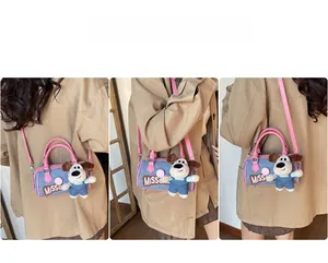 Detail of denim Boston bag with pink leather straps and cute plush dog charm