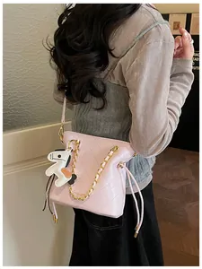 Detail of pink quilted bucket bag with gold chain strap and horse charm accessory