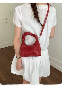 Red glossy pleated crescent handbag with cloud handle and adjustable strap shown on model