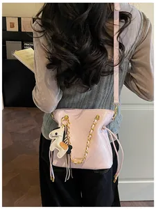 Pink quilted bucket bag with chain strap and horse charm worn by model