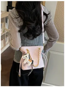 Detailed view of pink quilted bucket bag featuring a horse charm and gold chain strap