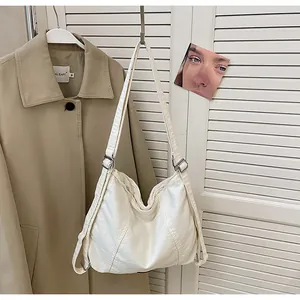 Detail van witte gewaxte leren tote tas met zilveren gesp en verstelbare schouderband