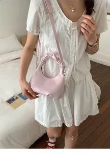 Detail of light pink shoulder bag with a stylish pleated scrunchie handle and PU leather texture