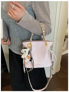Close-up of pink quilted leather bucket bag with golden chain and horse charm detail