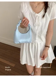 Detail of light blue pleated handbag with cloud shape and soft glossy leather texture
