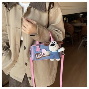 Detail of blue denim Boston bag with pink handles and cute puppy plush pendant