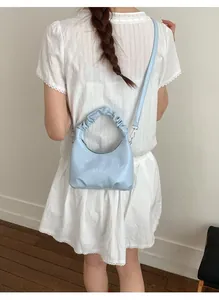 Model showing a baby blue crescent bag with unique ruched handles and silver hardware