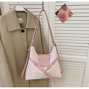 Detail van een roze contrasterende hobo-tas met een decoratieve kruisband en gesp