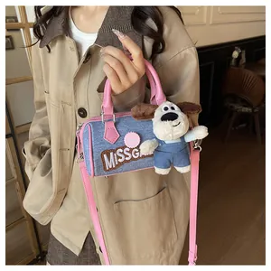 Detail of denim Boston bag with pink leather straps and cute puppy plush pendant