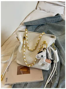 Close-up of white quilted leather bucket bag with gold chain strap and horse charm detail