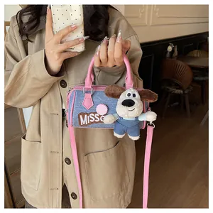 Detail of denim blue Boston bag with pink leather trim and cute puppy plush charm