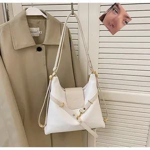 Detailopname van witte leren tas met gouden hardware en beige magnetische klepsluiting