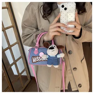 Close-up of blue denim Boston bag with pink leather trim and cute puppy plush charm