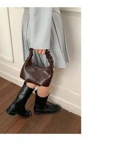 Detail of dark brown hobo bag featuring a pleated handle and vintage wax leather texture