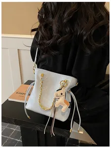 Close-up of light blue quilted bucket bag with gold chain and horse-shaped charm pendant