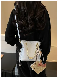 Close-up of quilted light blue bucket bag with leather horse charm and gold chain strap