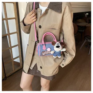 Detail of blue denim Boston bag with pink leather trim and a cute puppy plush charm