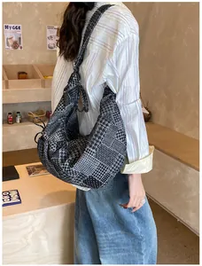 Detailed view of the large denim crescent bag with mixed check patterns worn by model