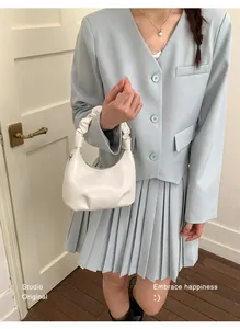 Detail of white matte leather handbag featuring trendy ruched handle and pleated base
