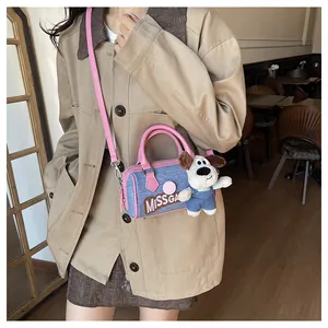 Detailed shot of a blue denim mini Boston bag with pink straps and a cute dog plush toy charm