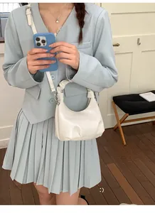 Detail of white pleated handle handbag with shoulder strap on a blue suit outfit