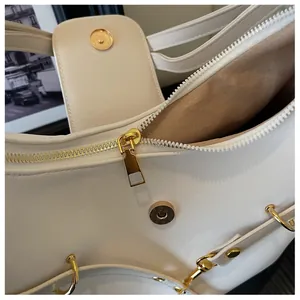 Detail van crème draagtas met gouden hardware en gladde kunstlederen structuur