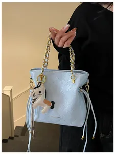 Detail of light blue quilted bucket bag with golden chain and horse charm pendant