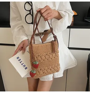 Détail du sac beige tissé à la main avec texture de pétales et breloques fraises
