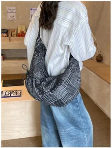 Detail view of large denim patchwork tote bag with side drawstring in a cozy lifestyle setting