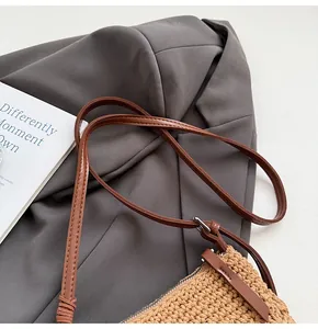 Gros plan d'un sac bandoulière tissé avec lanière en cuir marron et zip en métal argenté