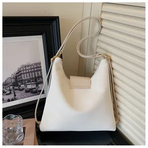 Detail van verstelbare leren riem en goudkleurige metalen hardware op een crème tas