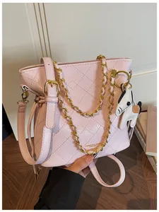 Detailed view of pink quilted bucket bag with gold chain and black pony charm