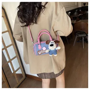 Detail of blue denim Boston bag with pink handles and cute puppy plush pendant