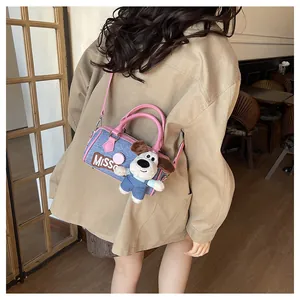 Detail of blue denim Boston bag with pink straps and a cute plush dog pendant