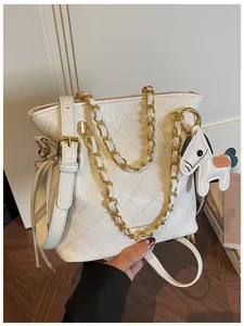 Detail of white quilted bucket bag with gold chain, leather strap and horse charm