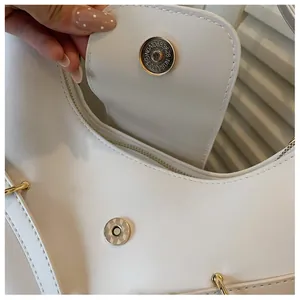 Detailopname van de magnetische sluiting en de binnenrits van de witte lederen tas