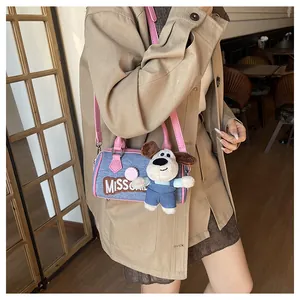 Detail of blue denim Boston bag with pink leather trim and a cute puppy plush charm