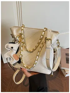 Close-up of quilted white bucket bag with gold chain and puppy charm detail
