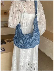 Detail of blue denim patchwork crescent bag on a model wearing a white lace dress