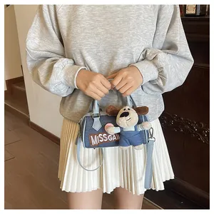 Blue denim Boston bag with plush puppy pendant shown on model in casual outfit