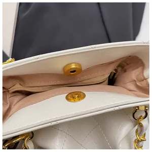 Close-up of quilted handbag showing magnetic snap closure and gold chain hardware detail