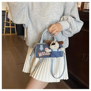Detail of blue denim Boston bag with MISS GAI embroidery and a cute puppy plush charm
